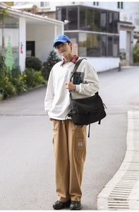 Street style shot of a black canvas messenger bag paired with khaki cargo pants