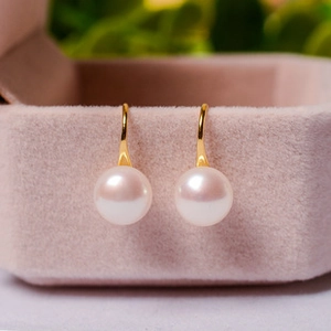 Dettaglio di orecchini con perle naturali e ganci dorati su astuccio in velluto rosa