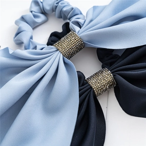 Detail of blue and black fabric hair scrunchies with rhinestones and elegant bow design