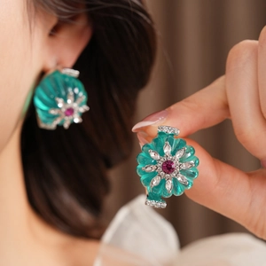 Detailed view of turquoise flower earrings with ruby centers and silver plating