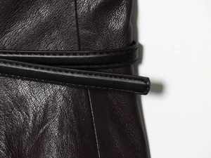 Détail d'une jupe en similicuir bordeaux avec texture grainée et ceinture noire nouée