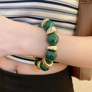 Detail of green malachite beads and golden metal spacers on a stylish wrist bracelet