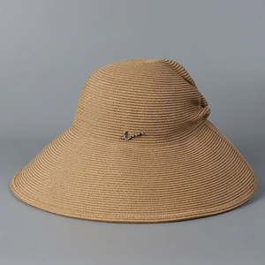 Detailed view of natural straw sun hat weave featuring a sleek silver metal logo accent