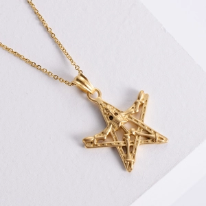 Gothic punk style 18K gold star and skull pendant necklace on a decorative stone base