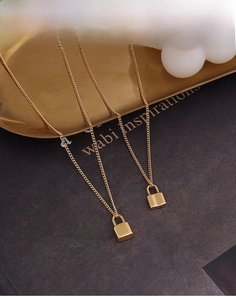Detail of 18k gold-plated lock pendant necklaces on a minimalist gold display tray