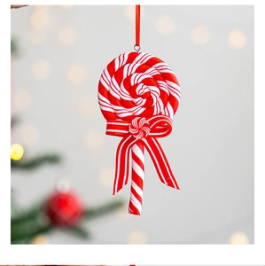 Close-up of red and white striped lollipop Christmas ornament with ribbon on a tree