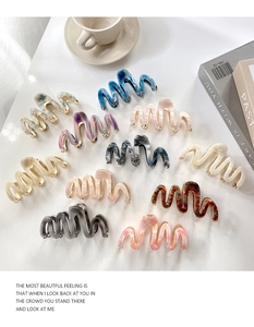 Close-up of wavy acetate hair claws with gold metal teeth in various marble patterns