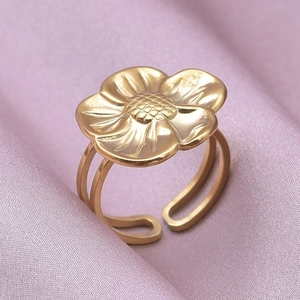 Detailed macro view of a vintage floral gold ring on soft purple silk fabric