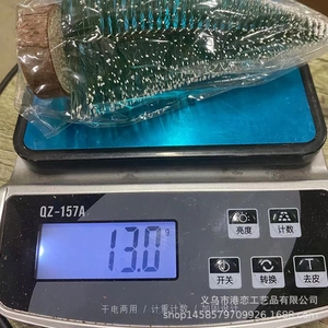 Miniature snow-dusted artificial Christmas tree on scale showing 13g product weight