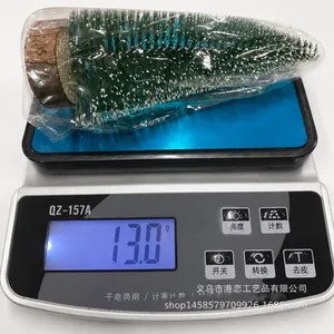 Miniatur-Weihnachtsbaum mit Kunstschnee auf Waage zur Anzeige des 13g Produktgewichts