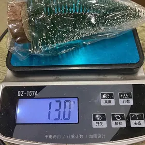 Mini sapin de Noël artificiel enneigé sur balance montrant le poids du produit de 13g