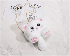 Detail view of white plush cat purse with gold metal chain strap on textured fabric
