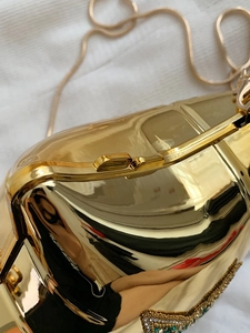 Detail of gold hard shell evening bag hinge with intricate bead embroidery and snake chain