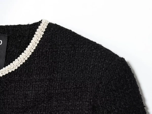 Detail einer schwarzen Tweed-Jacke mit cremefarbenem Webbesatz am Halsausschnitt