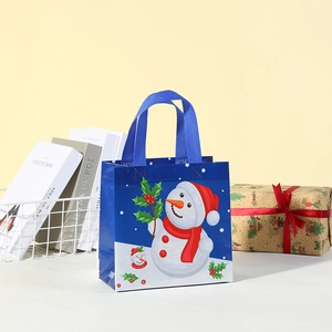 Detail of blue non-woven Christmas gift bag featuring festive snowman and holly leaf prints