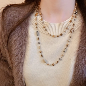 Close-up of layered geometric beaded necklace with gold plating for sweater styling