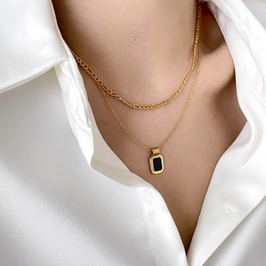 Double-layer gold necklace set featuring black onyx pendant on a white silk shirt