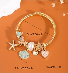 Detailed view of starfish shell charms and heart pendant on golden bracelet