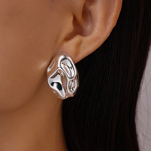 Macro shot of liquid metal style silver earring with irregular molten lava design on model