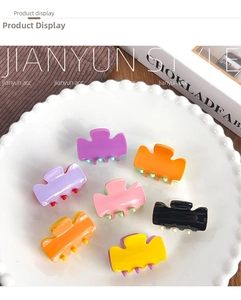 Detail view of 7 colorful acrylic hair claws with contrast teeth on a white plate