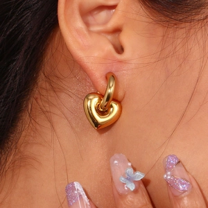 Close-up of a model wearing a gold-plated heart pendant hoop earring in stainless steel