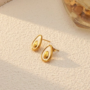 Detail of avocado-shaped gold stud earrings with white inlay on textured stone