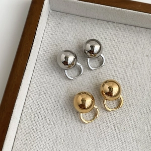 Minimalist geometric ball drop earrings in gold and silver finish on wooden tray