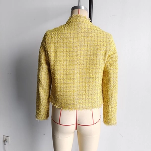 Detail view of yellow tweed jacket back featuring fringe trim and elegant textured fabric