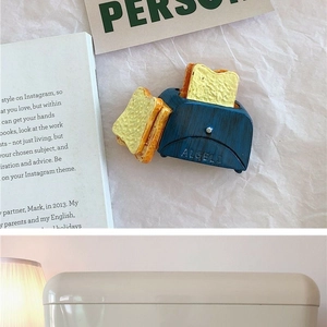 Miniature blue toaster toy with bread slices on paper and book scene background