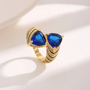 Detail of luxury gold ring featuring large blue triangle stones and black enamel stripes