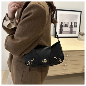 Detail view of a vintage black leather crescent shoulder bag with gold twist-lock and studs