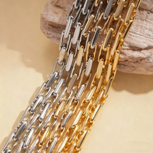Adjustable gold and silver minimalist paperclip chain necklace on a textured stone base