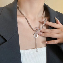 Detail of silver D letter pendant necklace with sparkling crystal inlay on a male model
