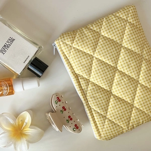 Macro detail of yellow checkered quilted cosmetic bag with diamond texture and accessories