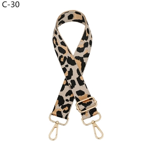 Close-up of leopard print bag strap with golden metal buckles and adjustable slider