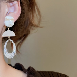 Detail view of large geometric resin earrings with marble texture on a female model