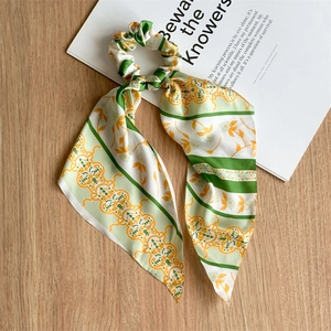 Close-up of silk bow scrunchie with floral pattern on a wooden surface and book