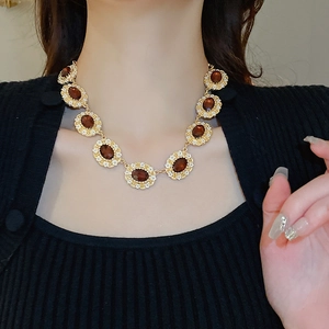 Detail of vintage gold necklace with amber oval gems and small white flowers on a model