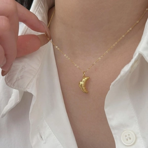 Close-up of 925 sterling silver croissant pendant necklace worn on a woman neck