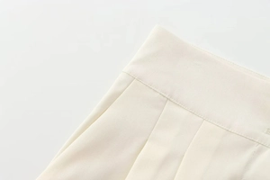 Gros plan de la taille en tissu tissé ivoire montrant coutures fines et détails plissés