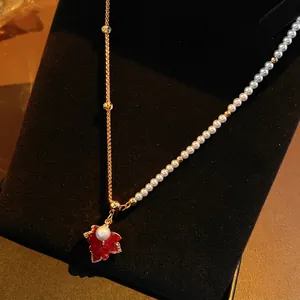 18K gold plated maple leaf necklace with pearls and zircons on a black display stand