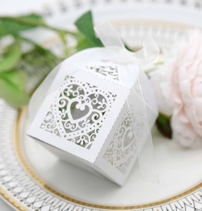 Detail of white laser-cut wedding favor box with heart patterns and satin ribbon bow