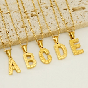 Detail of 18K gold plated stainless steel letter necklaces with hammered texture pendants