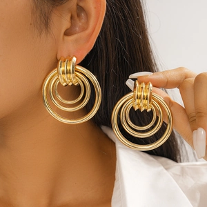 Detail view of gold geometric layered circular earrings worn by a model