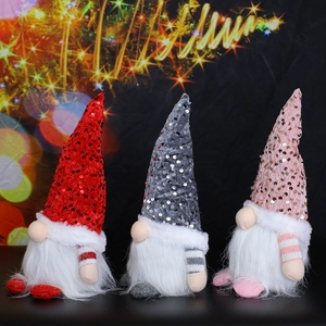 Three sequined Christmas gnomes with LED lights and plush beards on a black surface