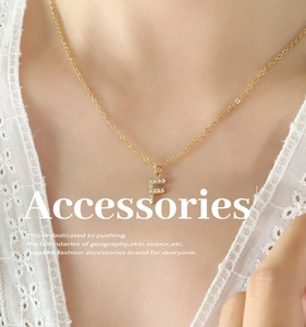 Detail of a gold titanium necklace with a zircon-inlaid letter F pendant on a model