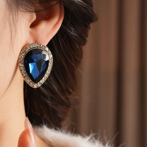 Gros plan détaillé de boucles d'oreilles goutte bleu foncé avec aiguilles en argent et strass