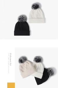 Detail der Strickmütze mit Zopfmuster und Kunstfellbommel in Schwarz, Weiß und Beige
