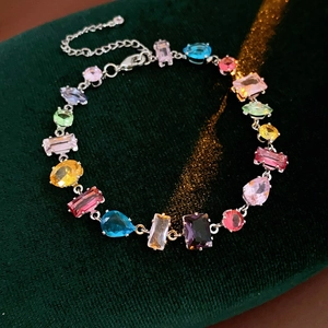 Detail of colorful zircon flower bracelet with multi-shape stones on green velvet