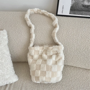 Detail of soft beige and white checkerboard plush shoulder bag on a cozy sofa